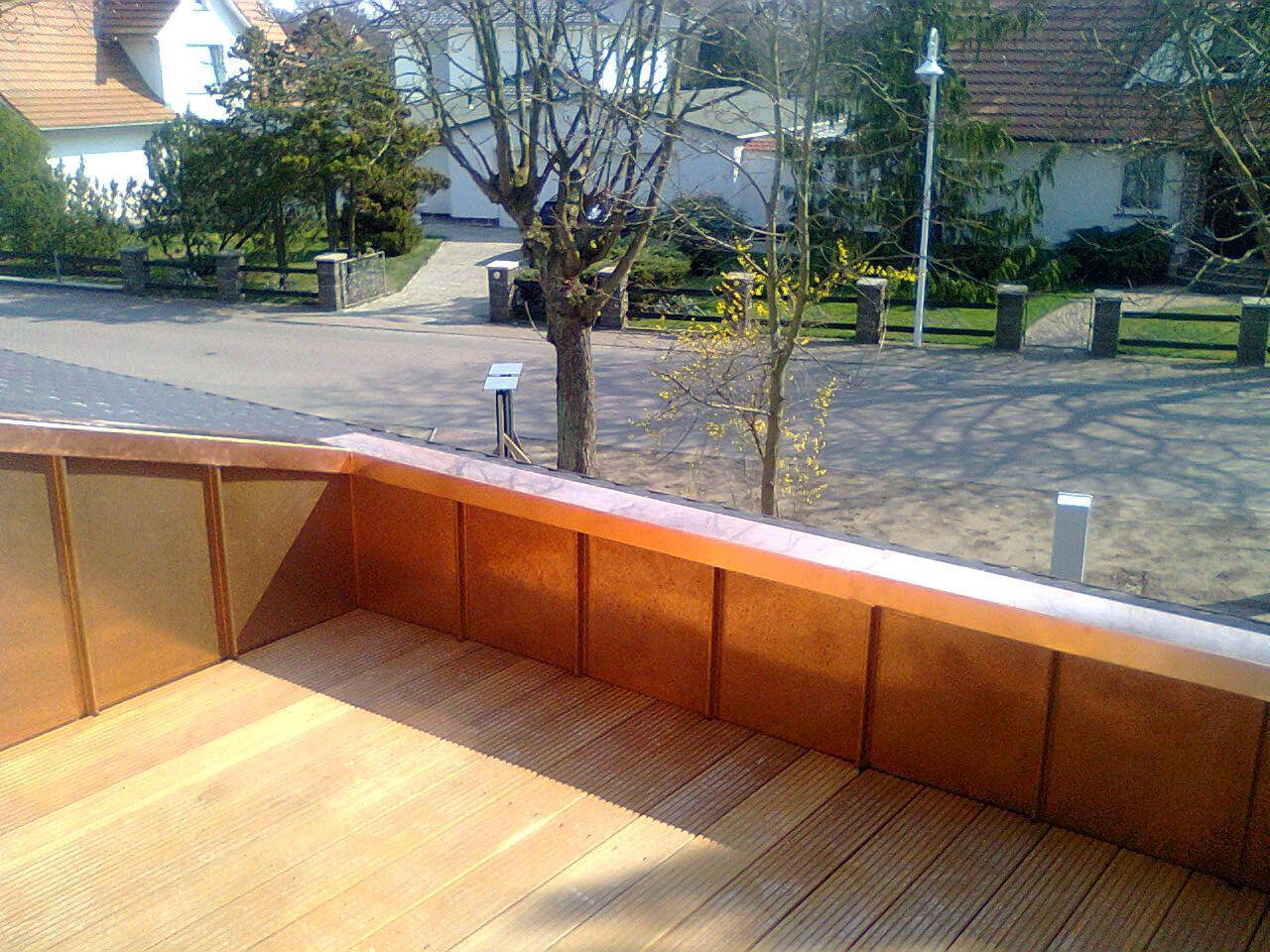 Holzterrasse mit Kupfereinfassung und Blick auf eine Wohnstraße.