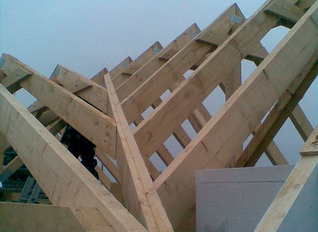 Im Bau befindliche hölzerne Dachstühle, schräg vor einem bewölkten Himmel.