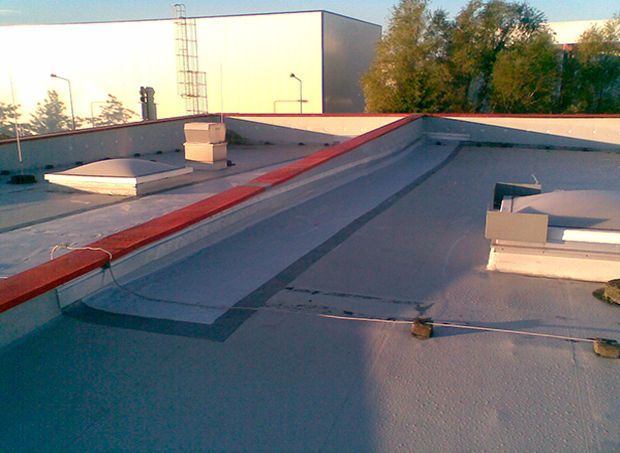 Flaches Gewerbedach mit Oberlicht, Belüftung und roter Zierleiste.