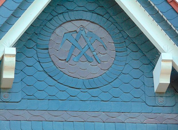 Blaues Dach mit kreisförmigem Emblem aus gekreuzten Spitzhacken.