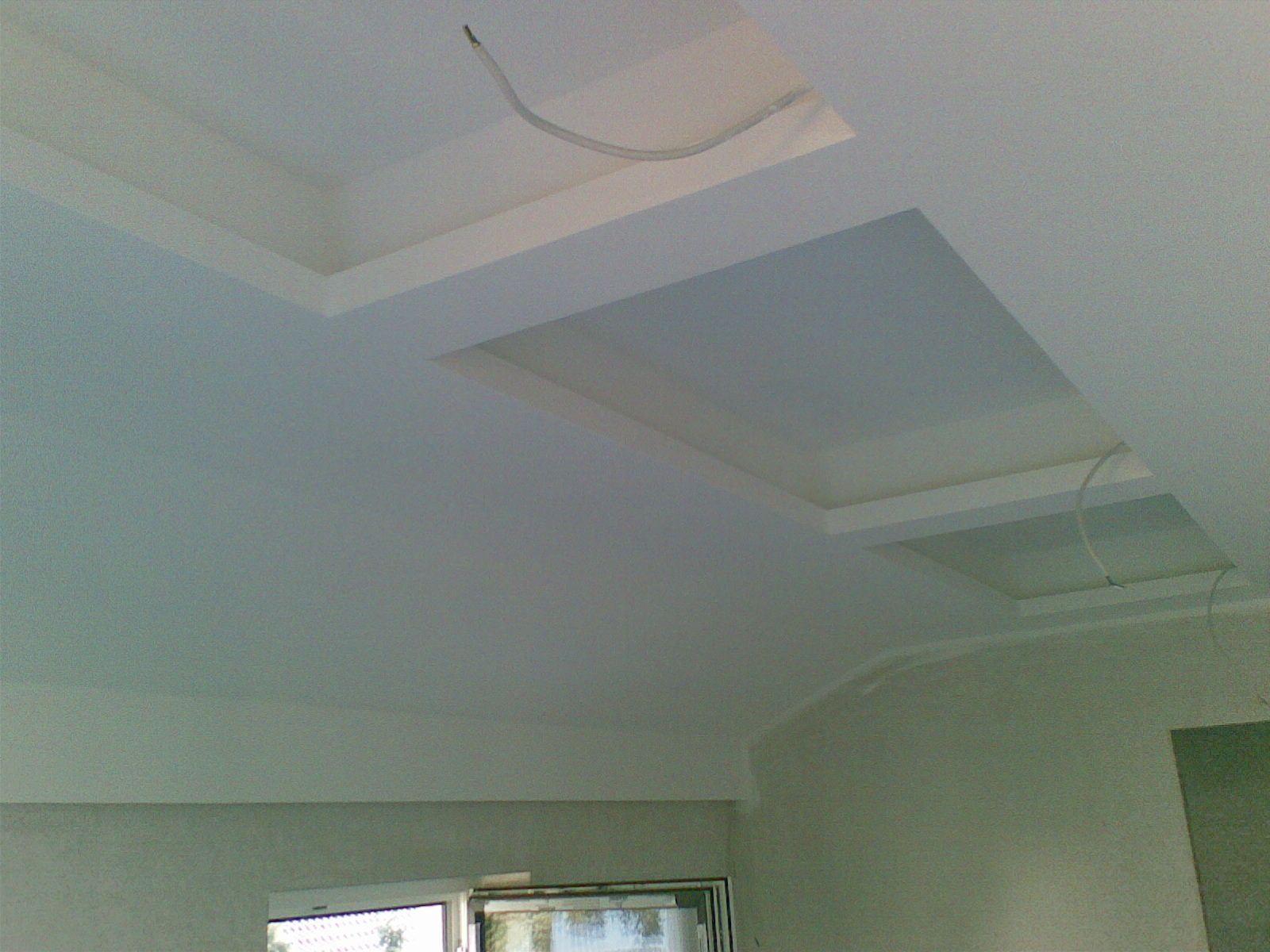 Weiße Decke mit eingelassenen Beleuchtungskästen und freiliegenden Kabeln.