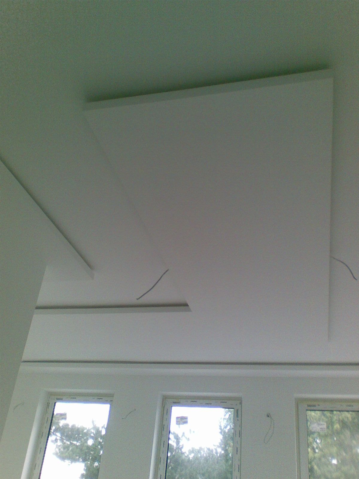 Weiße Decke mit Akustikpaneelen über den Fenstern.