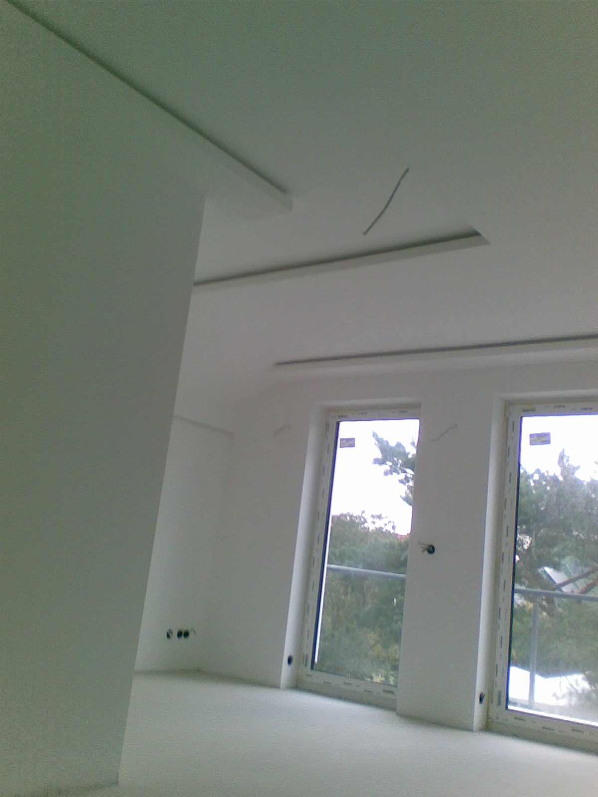 Weißer Raum mit Fenstern, Deckenleuchten und Säule.