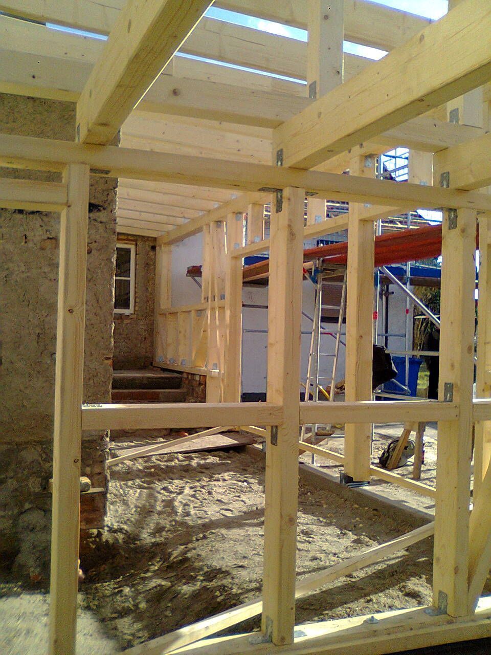 Holzrahmenkonstruktion an einem Steingebäude mit sichtbarer Tür und Treppe.