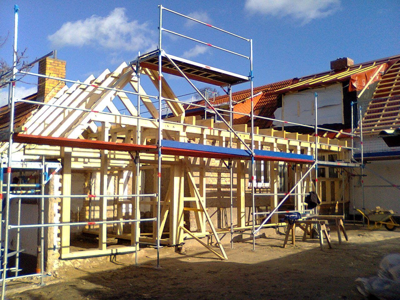 Beim Bau eines neuen Hausanbaus ist die Holzrahmenkonstruktion von einem Gerüst umgeben.
