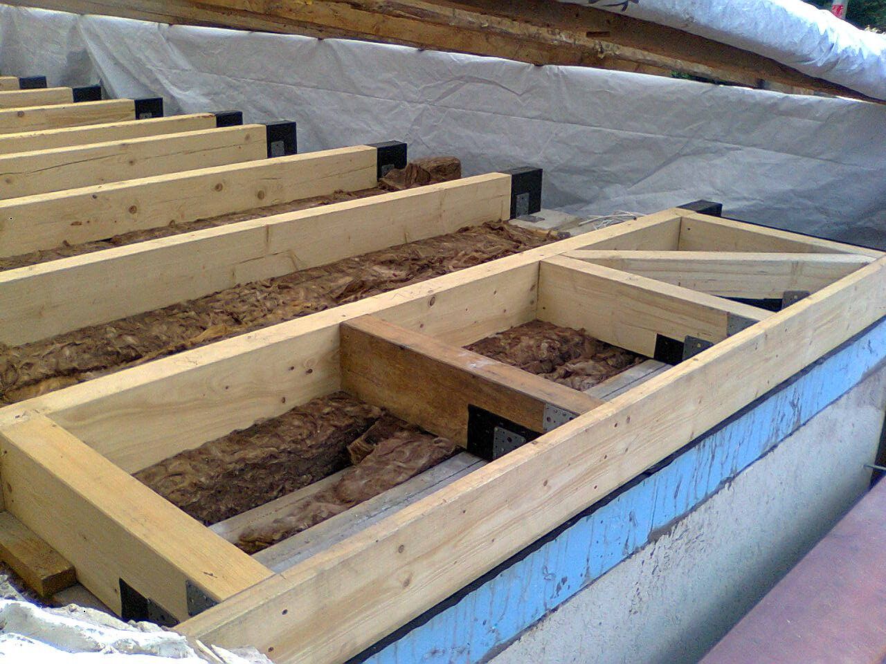 Holzrahmen und Dämmung werden auf einem Dach montiert.