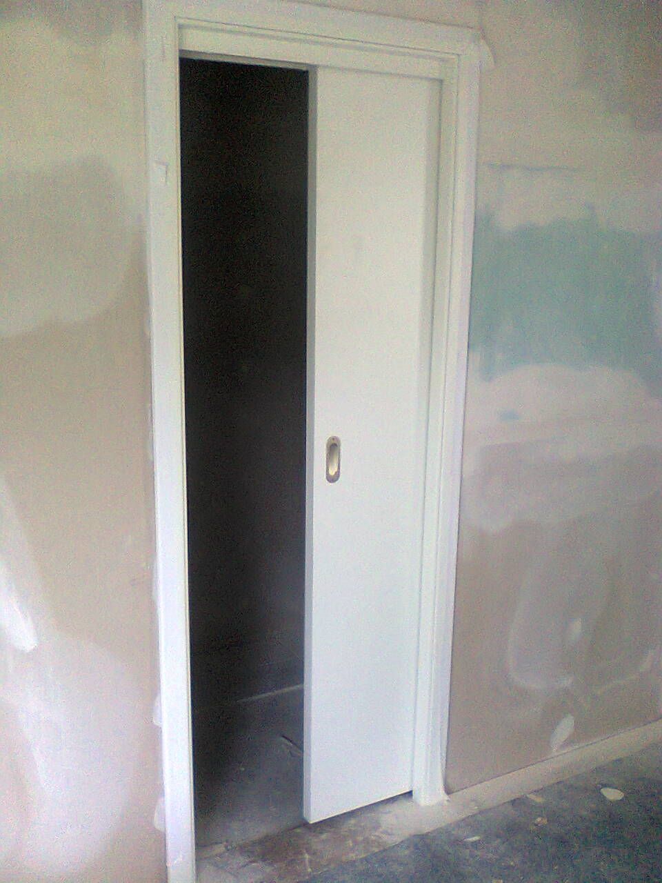 Weiße Schiebetür in unfertigem Raum teilweise geöffnet.