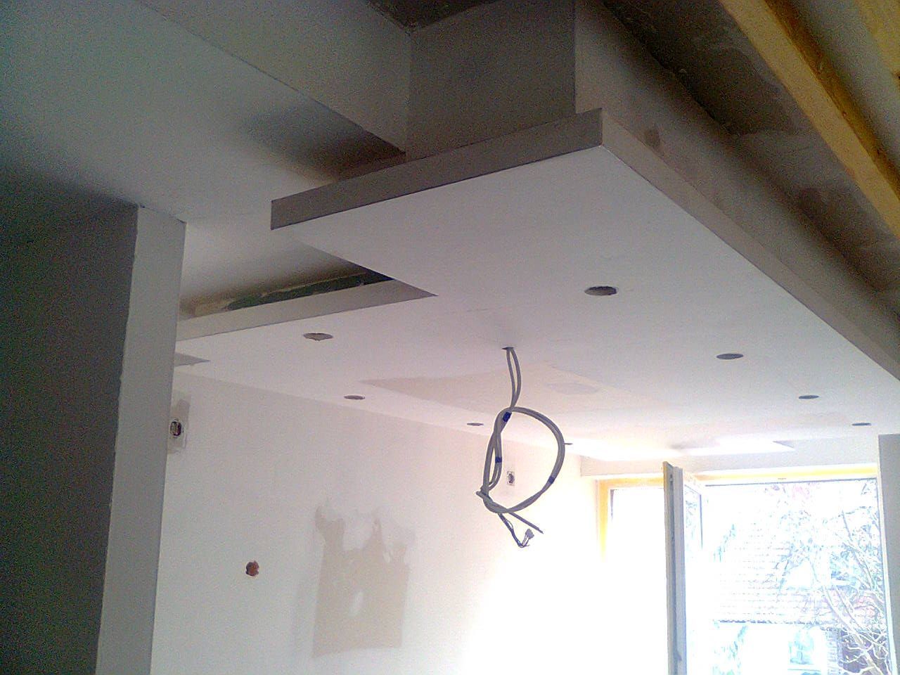Innenansicht im Bau, zu sehen ist eine weiße Decke mit Einbauleuchten und freiliegenden Kabeln.
