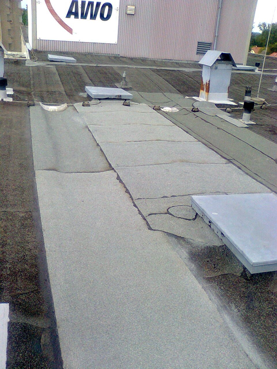 Balkon mit Metallgeländer, grauem Bodenbelag und weißer Außenwand.