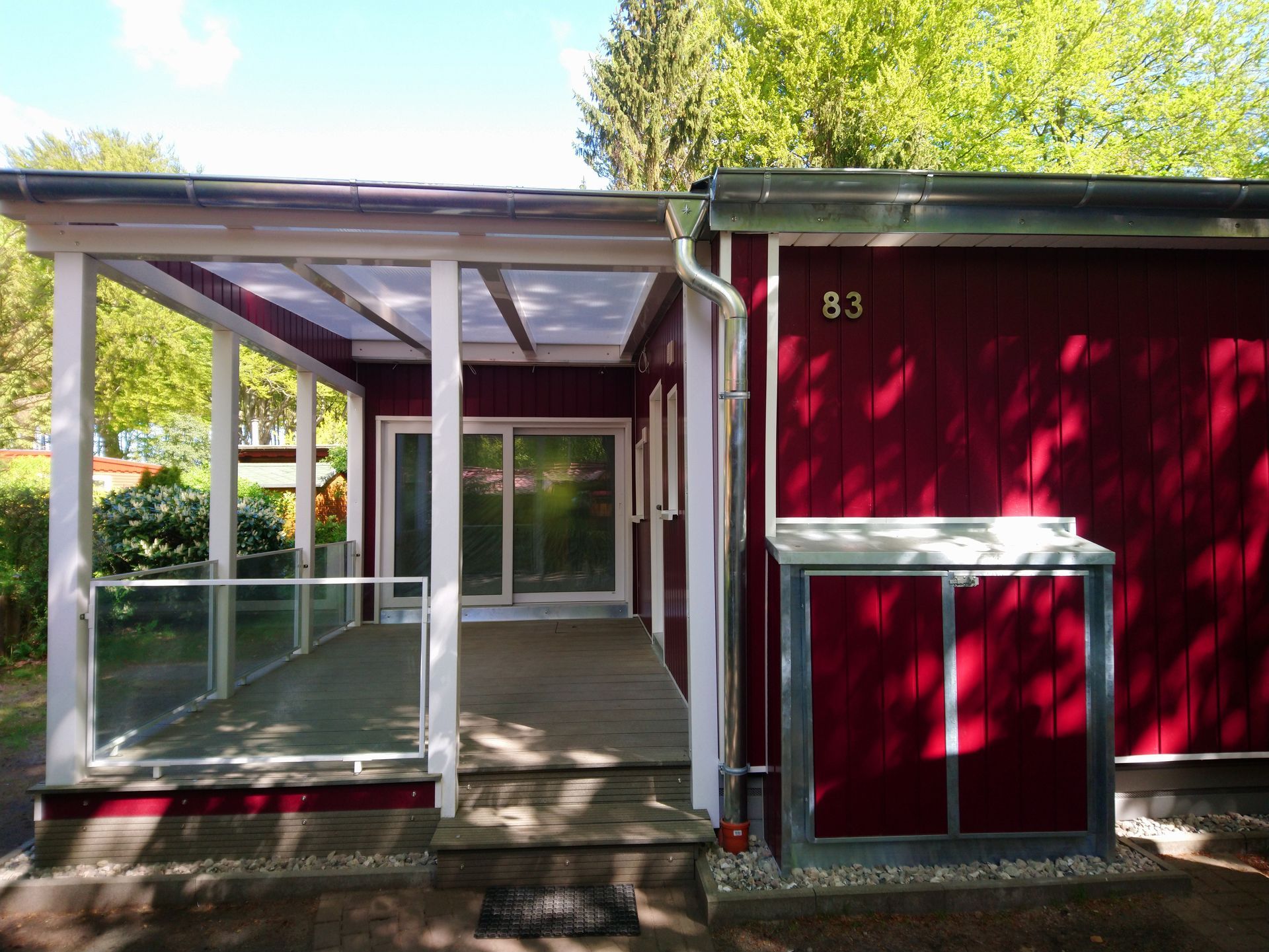 Rotes Gebäude mit überdachter Veranda und der Hausnummer 83.