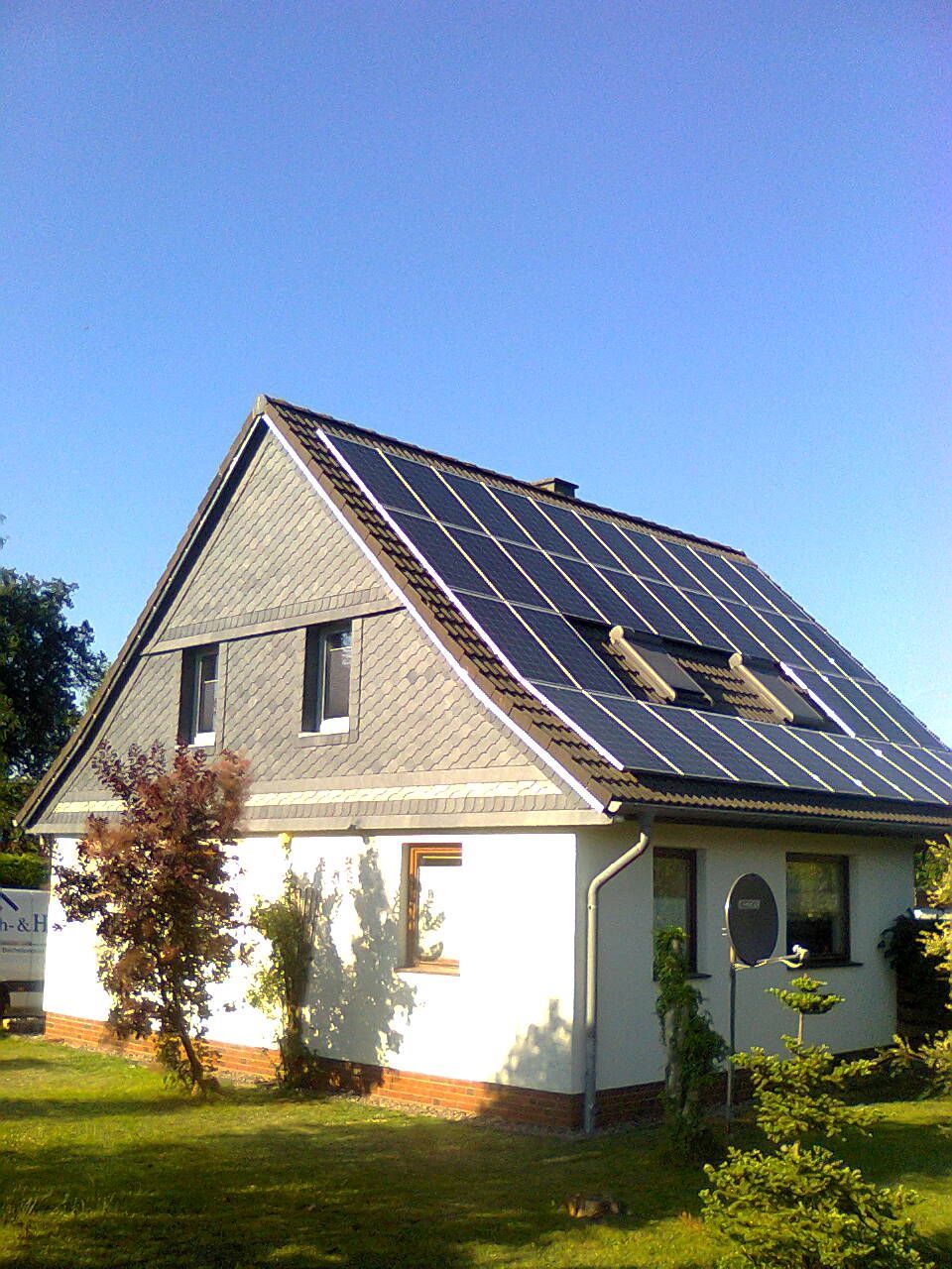 Haus mit Solarpaneelen auf dem Dach unter blauem Himmel.