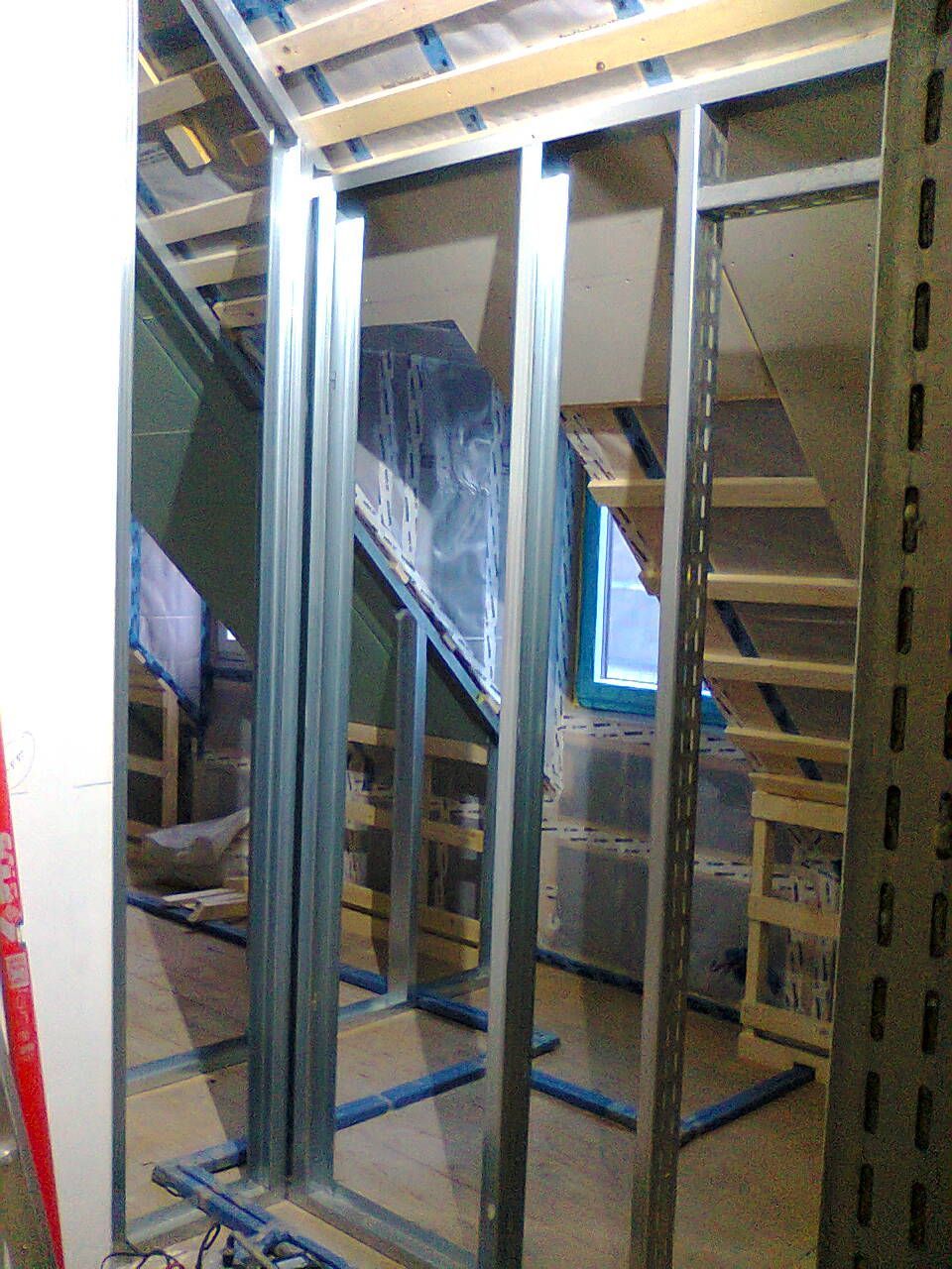 Metallrahmenkonstruktion eines Zimmers oder Schranks, bei der die Ständer und die Isolierung sichtbar sind.