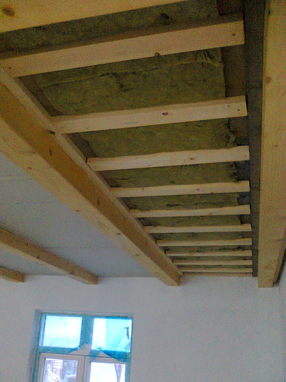 In der Decke, in der Nähe eines Fensters, sind Holzbalken mit Dämmung eingebaut.