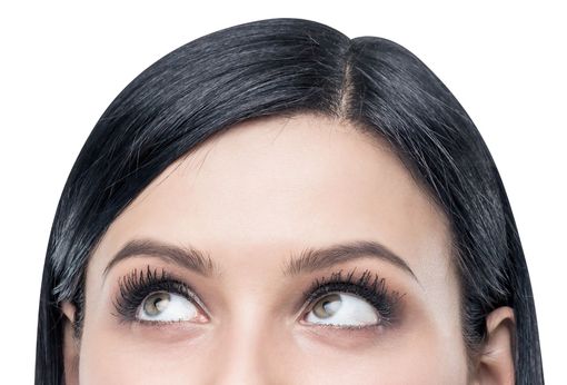 Mujer con cabello negro mirando hacia arriba, usando maquillaje.