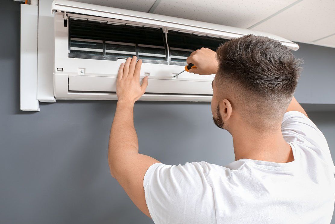 Un homme fait la maintenance d'un climatiseur
