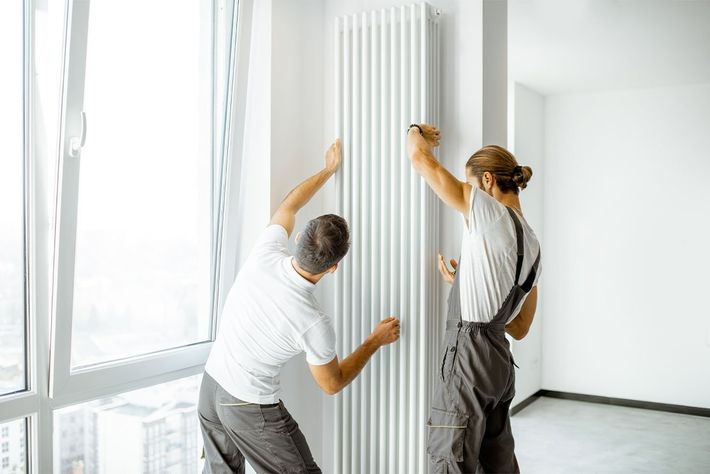 Deux hommes posent un radiateur vertical