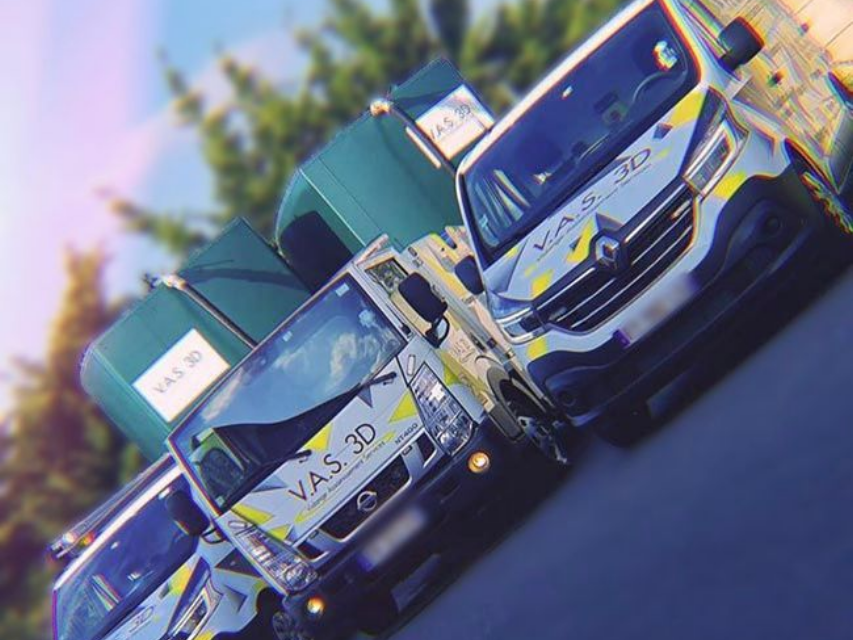 Plusieurs camionnettes et des bennes à ordures vertes étaient garées en plein soleil.