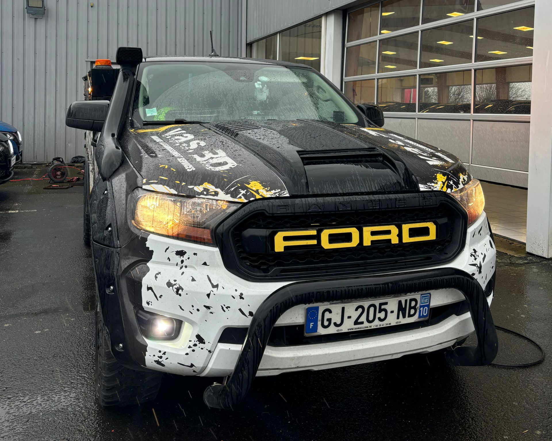 Fourgonnette portes ouvertes stationnée de nuit dans une rue pavée, éclairée par des lumières intérieures.