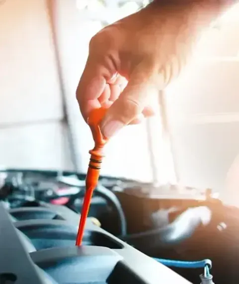 Comprobación manual del nivel de aceite del coche con una varilla naranja situada debajo del capó.