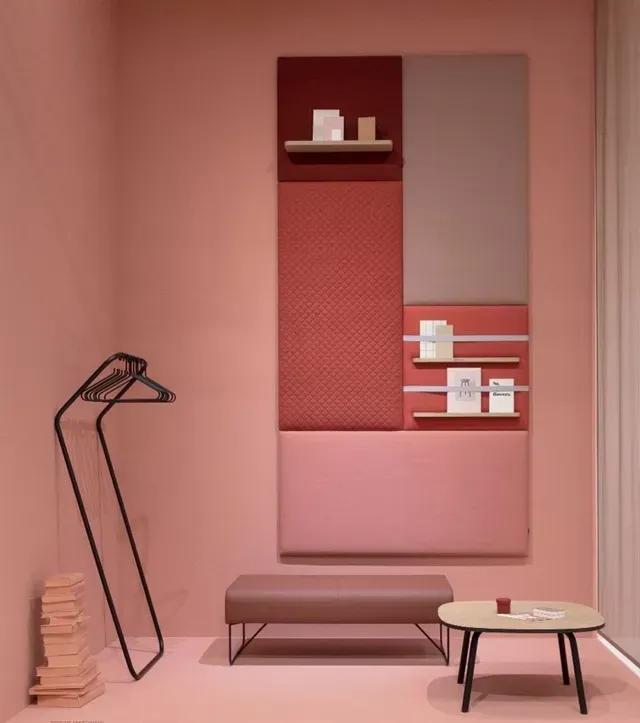 Una habitación con paredes rosas, un banco, una mesa y una percha.
