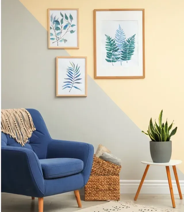 Una sala de estar con una silla azul, una lámpara y cuadros en la pared.