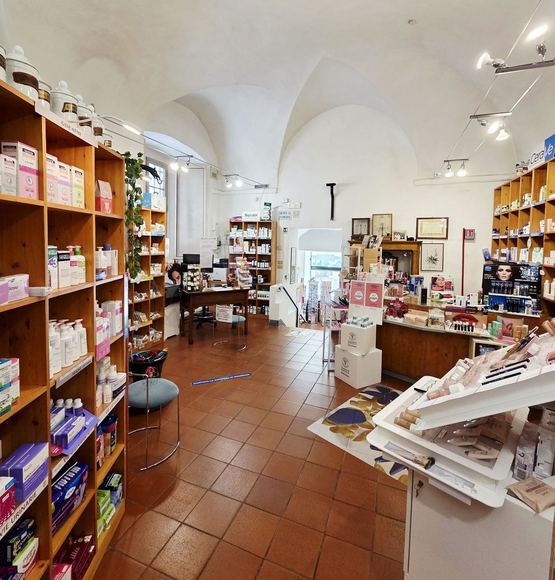 Una farmacista bionda in camice bianco prende i farmaci da uno scaffale in una farmacia ben illuminata.