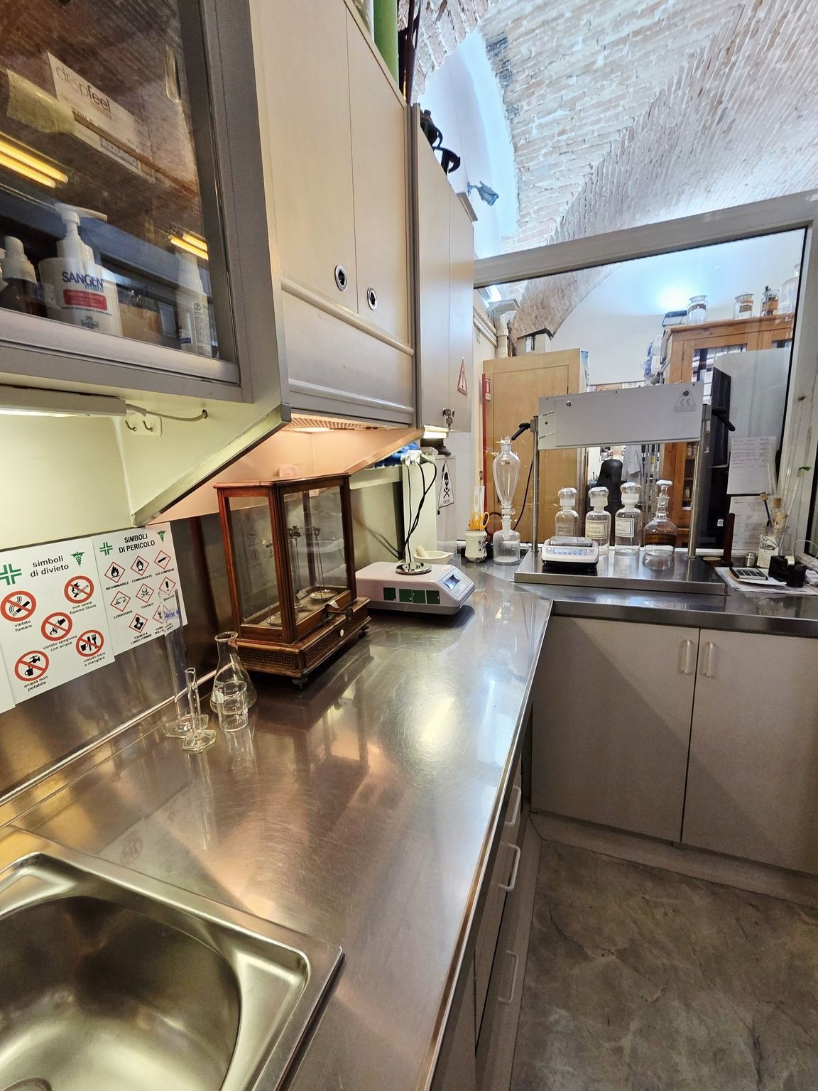 Laboratorio della farmacia con ripiani in acciaio inox, lavello, armadietti 