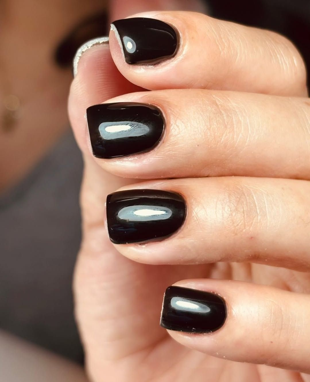 Primer plano de una mano con las uñas pintadas de negro brillante.