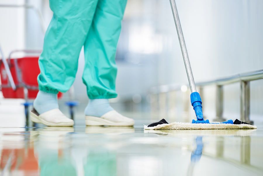 Una enfermera está limpiando el suelo de un hospital con un trapeador.