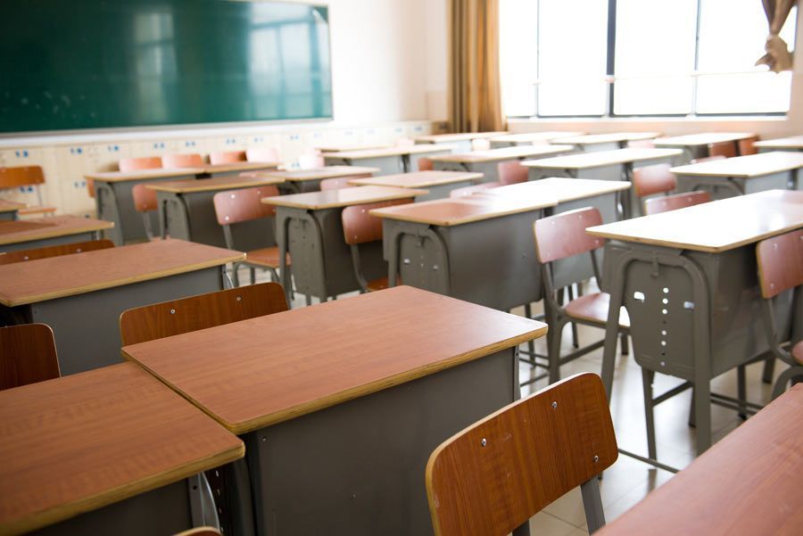 Un aula vacía con escritorios y sillas de madera.
