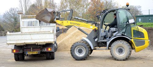 Une petite chargeuse décharge des matériaux à l'arrière d'un camion