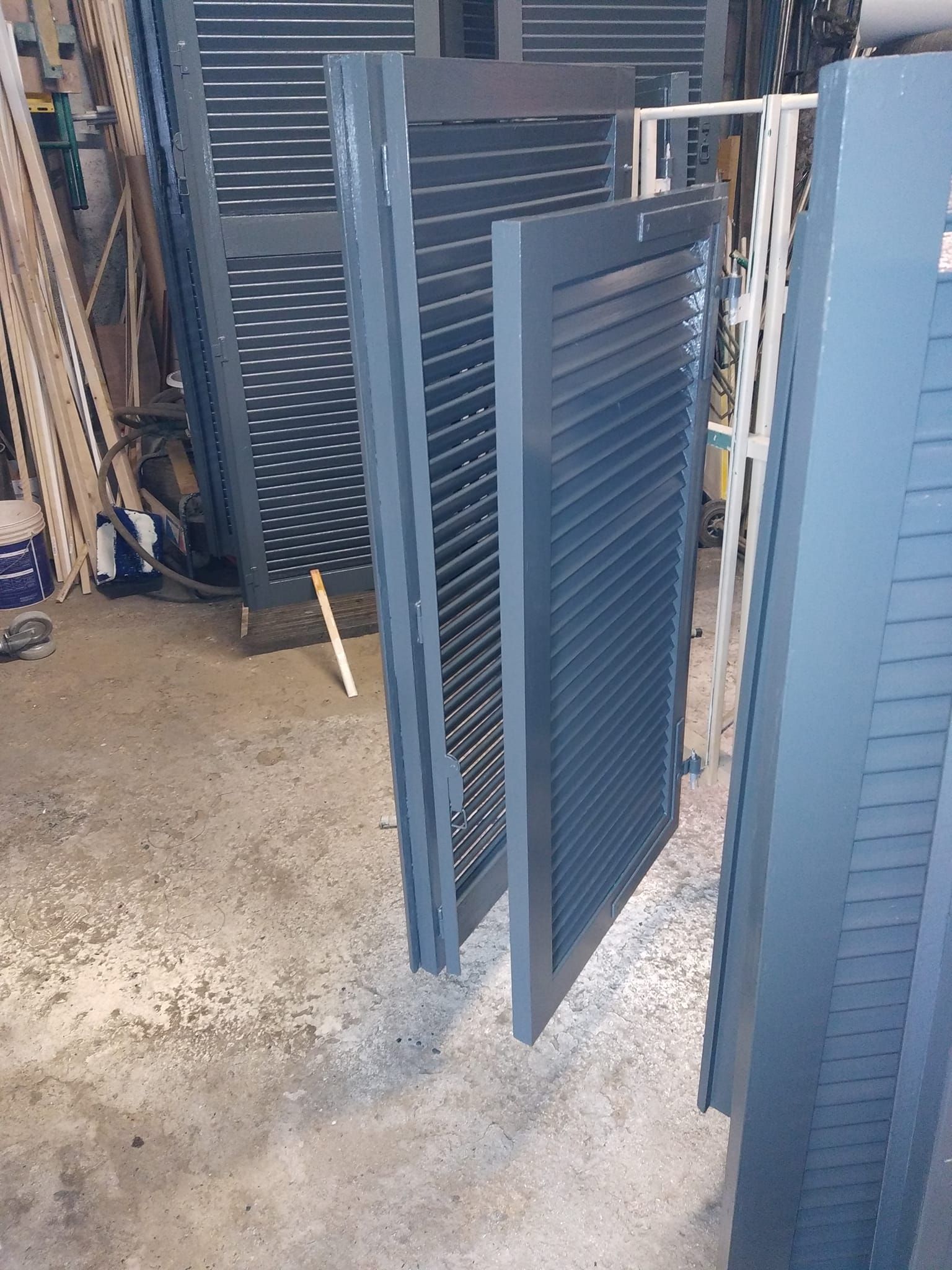 Volets gris adossés les uns aux autres dans un atelier.