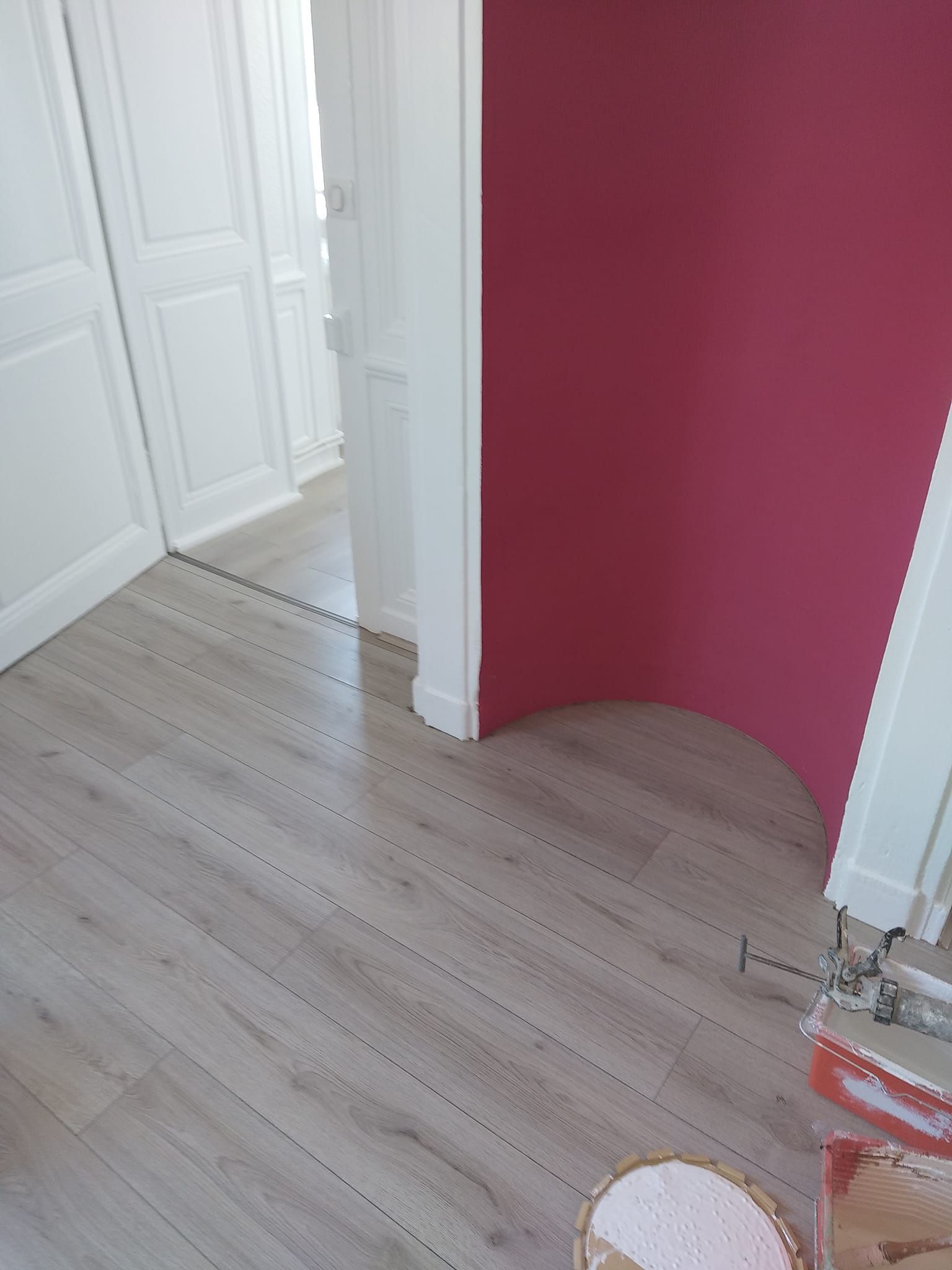 Un plancher en bois et un mur rose.