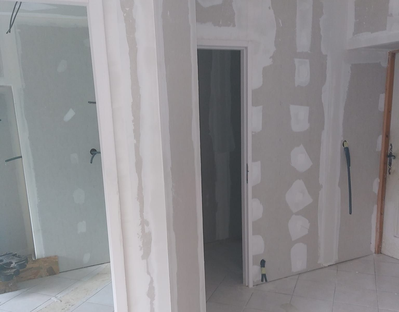 Intérieur avec construction en cloisons sèches; porte, colonne et murs partiellement finis.