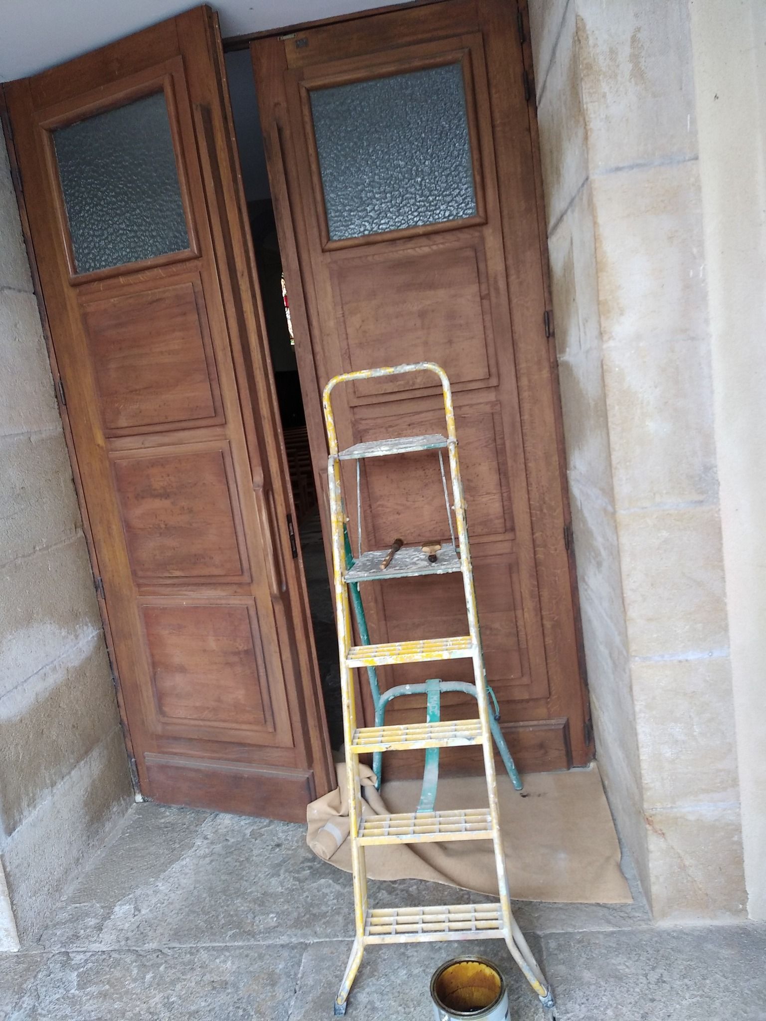 Portes doubles en bois ouvertes, avec une échelle jaune devant.