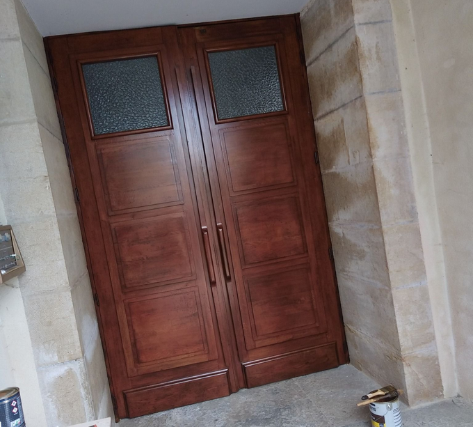 Portes doubles en bois avec panneaux de verre encastrés dans un mur en pierre.