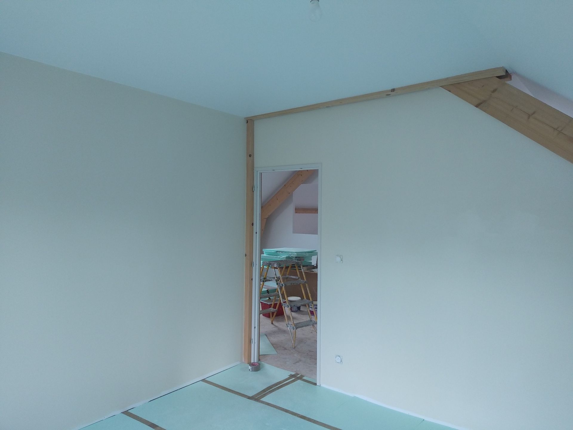 Pièce intérieure avec des murs blancs et des poutres en bois.