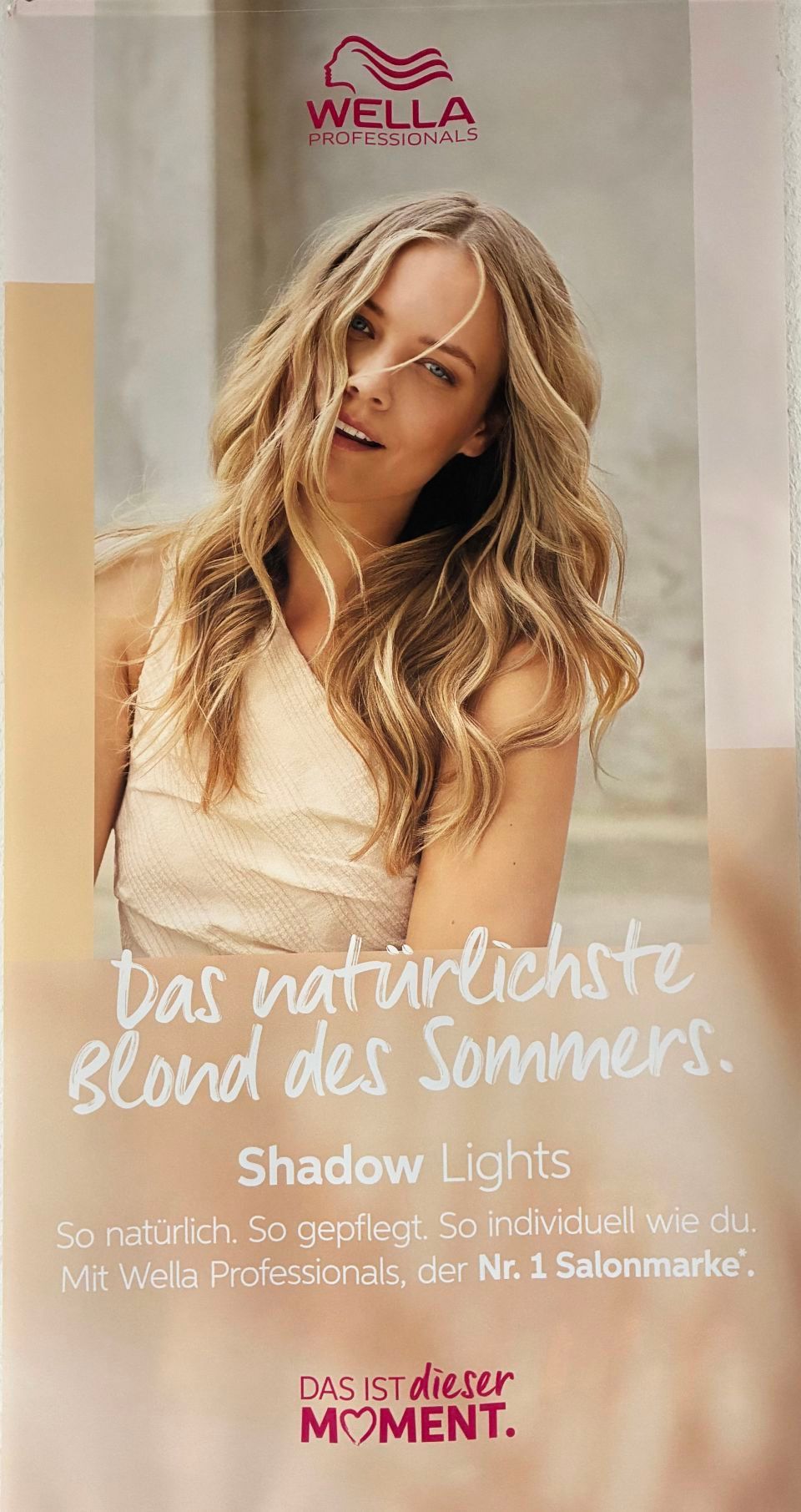 Wella-Werbung: Frau mit blondem, gewelltem Haar; Schriftzug „Shadow Lights“; natürliches Licht, Beigetöne.