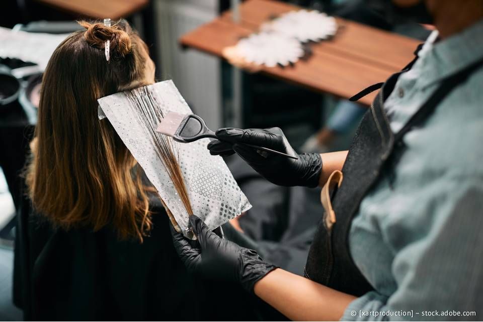 Friseurin trägt Haarfarbe mit Folie und Pinsel auf.