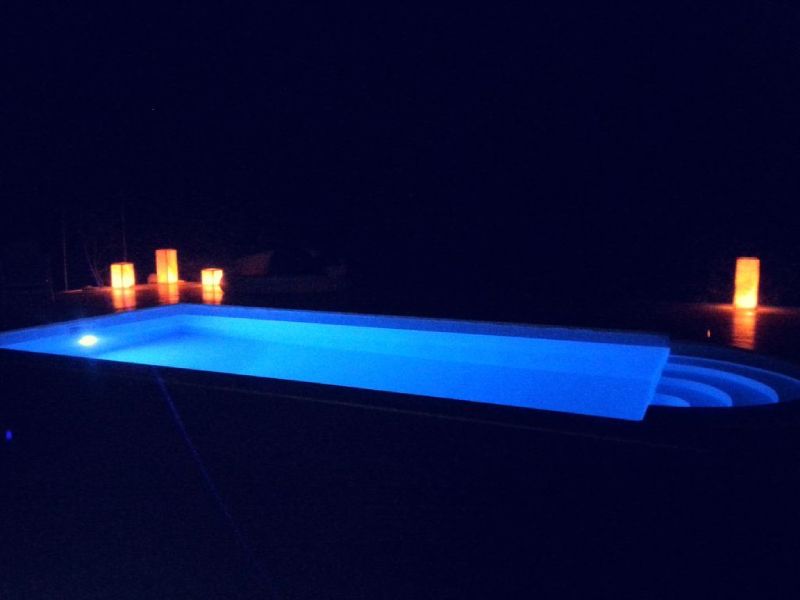 Ein Swimmingpool ist nachts mit Kerzen beleuchtet.