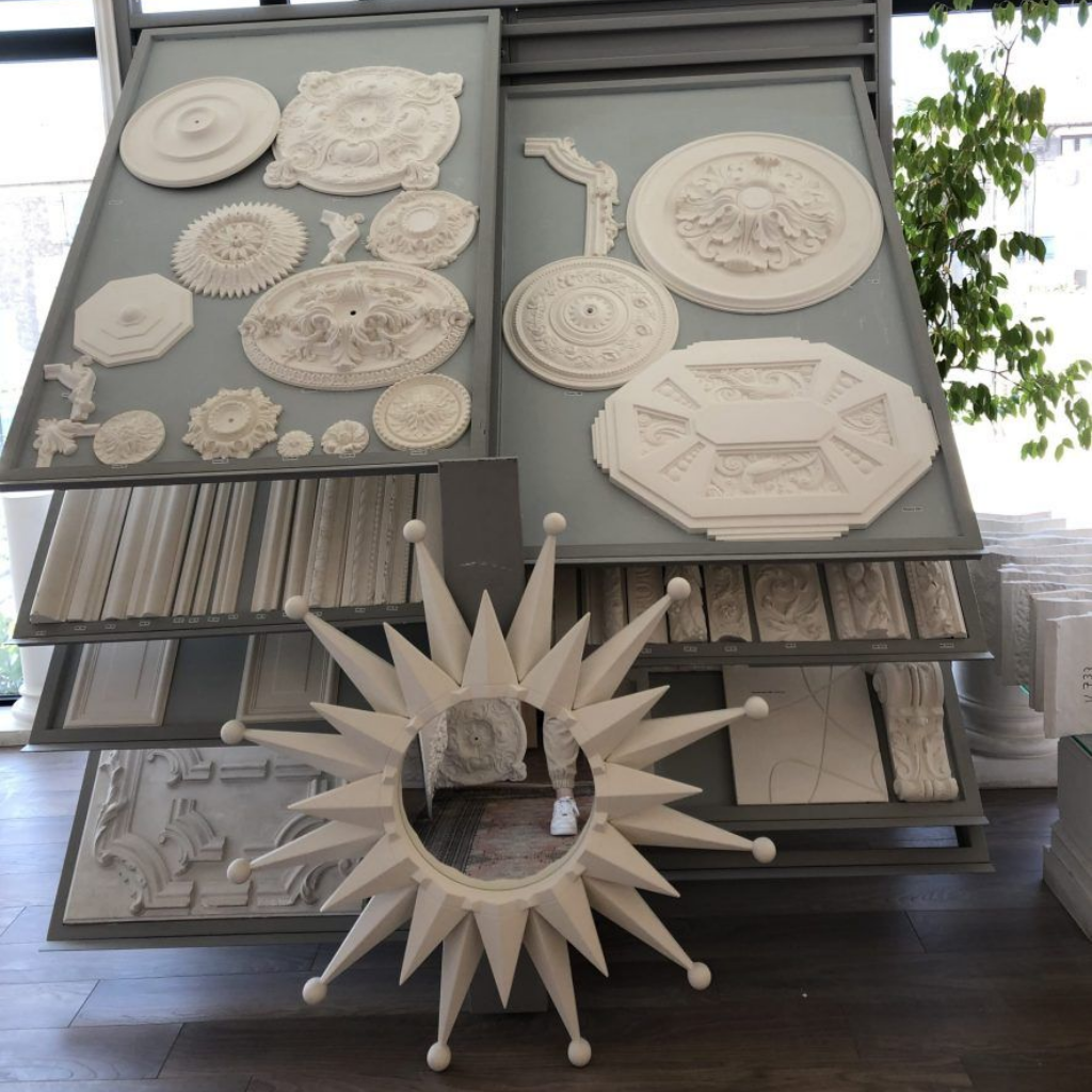 Un présentoir rempli de divers médaillons décoratifs en plâtre pour plafonds et d'échantillons de moulures.