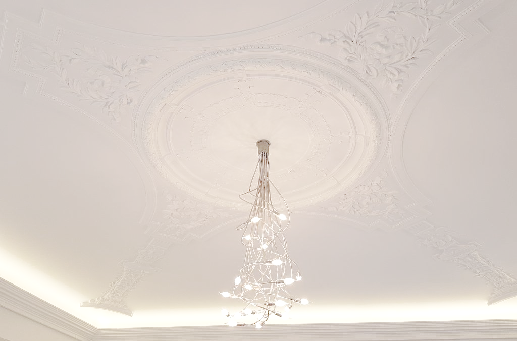 Un lustre moderne éclairé est suspendu à un médaillon circulaire orné en plâtre blanc au plafond.