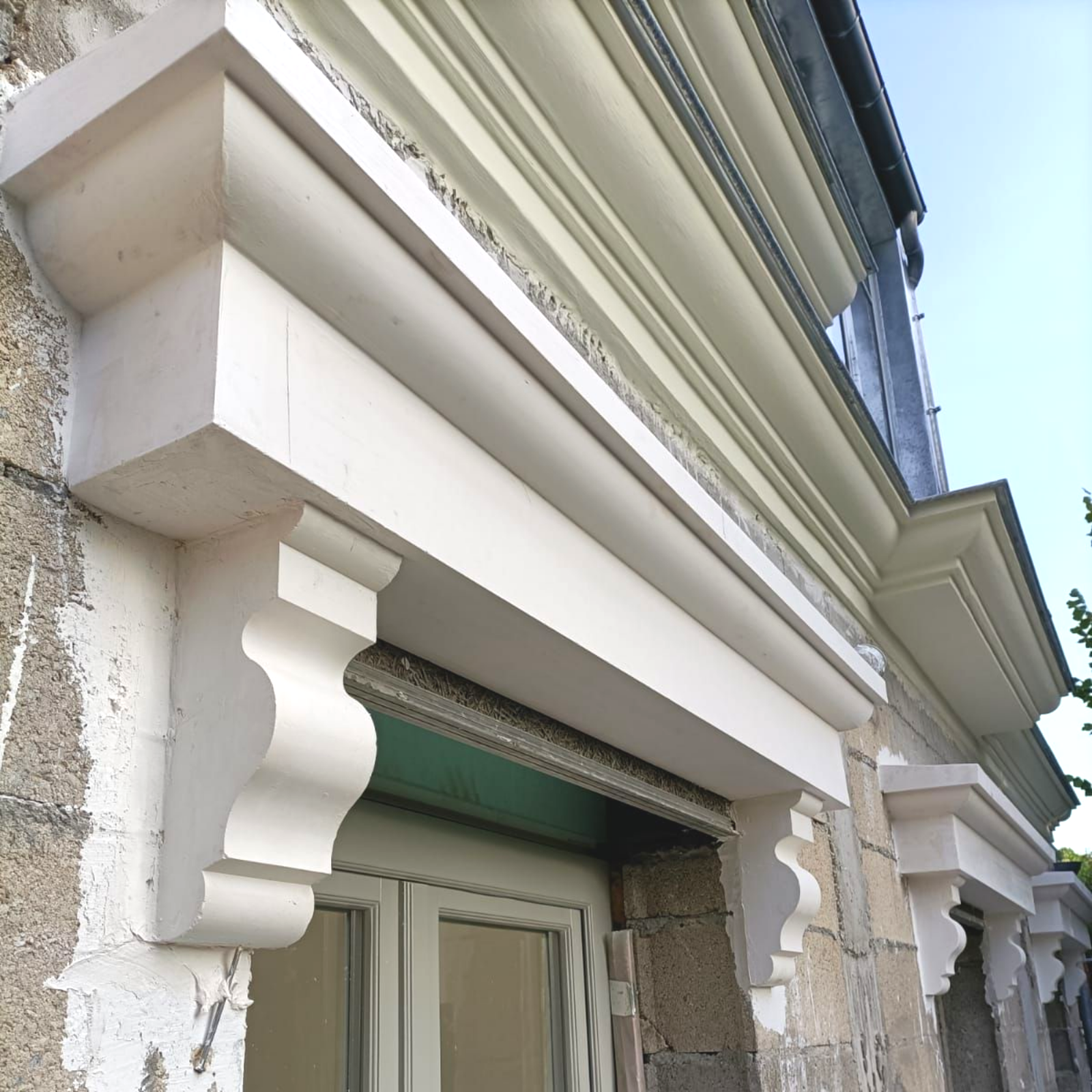 Vue en contre-plongée de linteaux de fenêtres en pierre blanche avec des consoles décoratives.