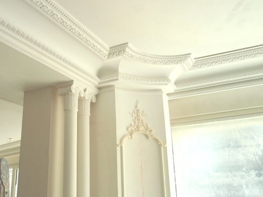 Détails architecturaux intérieurs comprenant des colonnes en plâtre, des moulures ornementales et des garnitures décoratives.