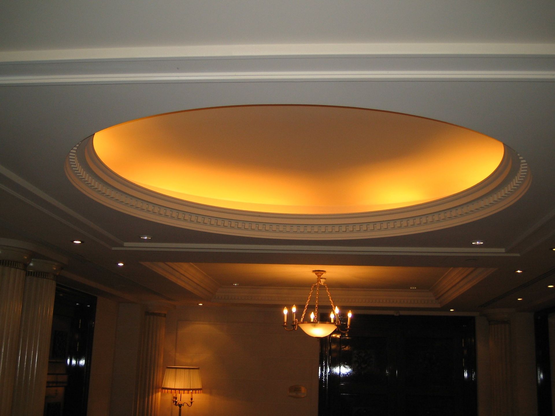Vue intérieure d'un plafond comportant une grande niche circulaire éclairée et un lustre suspendu.