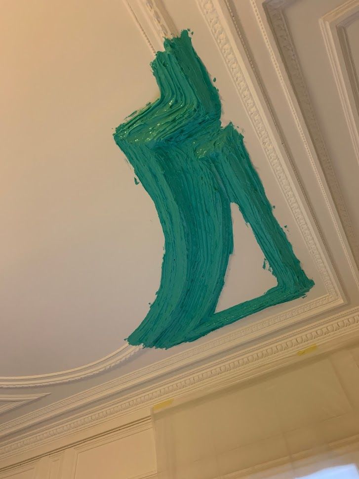 Une pâte épaisse et texturée de couleur turquoise, appliquée le long d'une moulure au plafond.