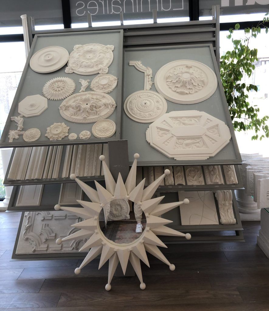 Un présentoir avec des médaillons de plafond en plâtre blanc et des moulures, devant lesquels se trouve un miroir mural.