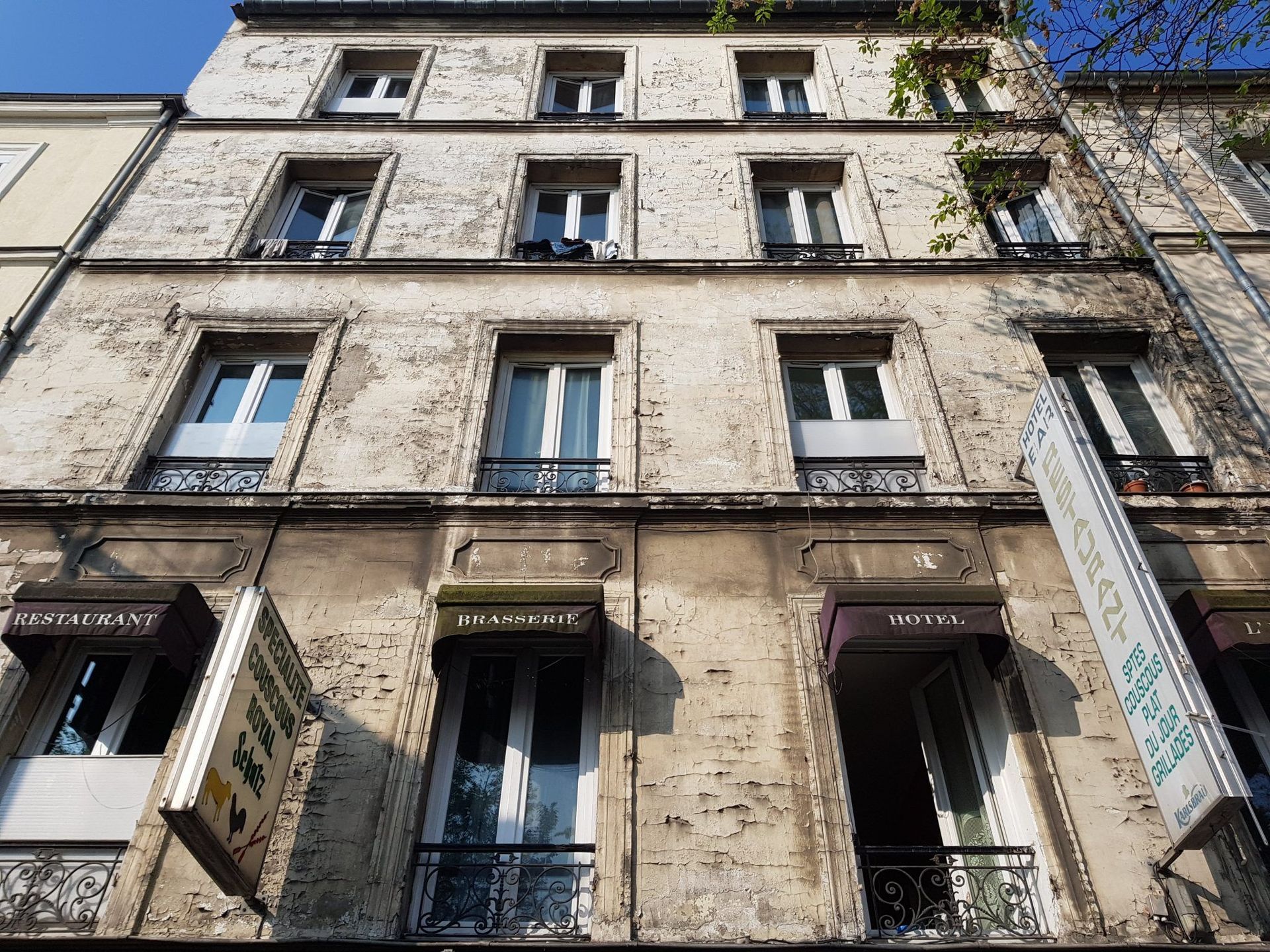 Vue en contre-plongée d'un immeuble délabré à plusieurs étages, aux murs de pierre décolorés.