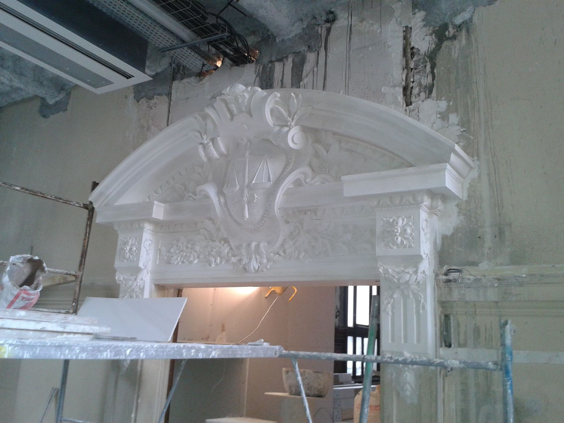 Une arche de porte en plâtre blanc ornée de détails architecturaux sculptés.