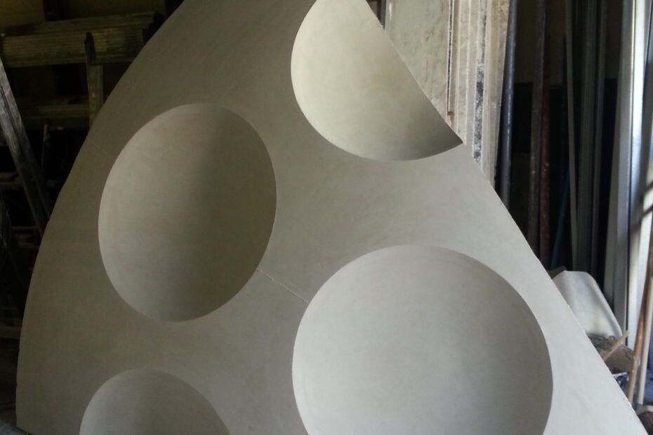 Panneau blanc incliné à découpes circulaires dans un atelier.